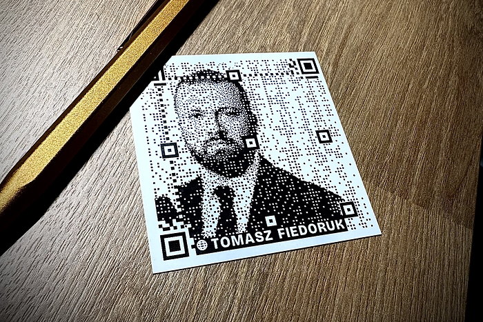 The printed card next to a pen for scale: a QR code of black dots forming a portrait.